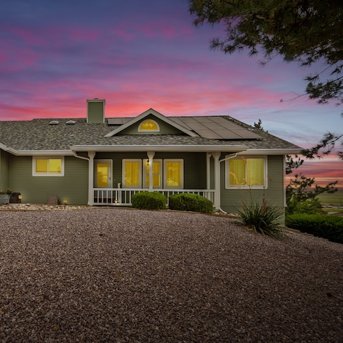 Ranch home with large rock yard at sunset.