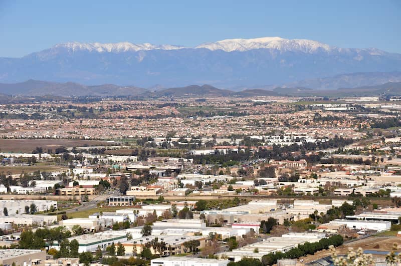 Distant view of a city in California with snow capped mountains in the background.