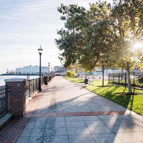 Tree lined walkway along waterfront with skyline in distance in West New York, New Jersey.