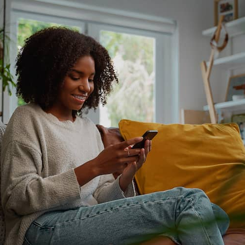 Woman on phone in living room, smiling.