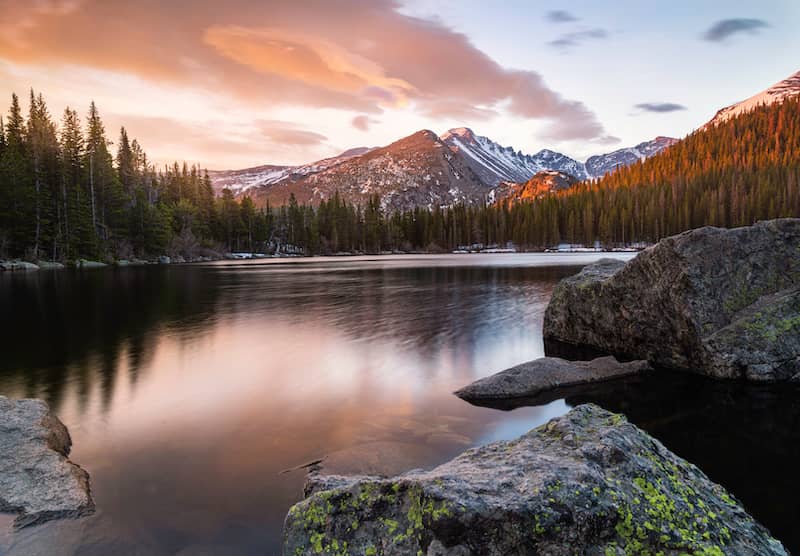 Bear Lake at sunrise with pine trees and mountains in the background.