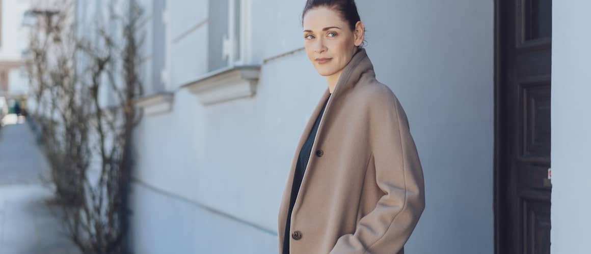 Modern woman in coat standing outside on a sunny day