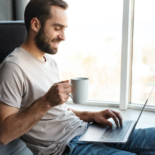 Young man sitting on a floor in the living room, depicting a young man seated on the floor in a living room setting.
