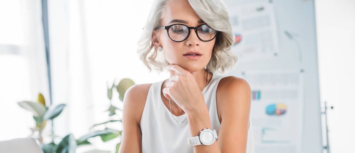 Woman with glasses working at desk.