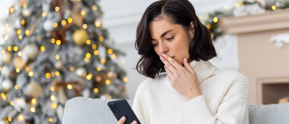 Upset woman sitting alone at home on sofa in living room near Christmas tree