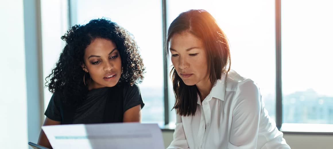 Two women looking over mortgage documents together at signing.