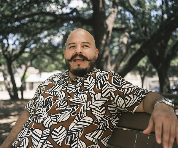 A man sits on a park bench while talking about home affordability.