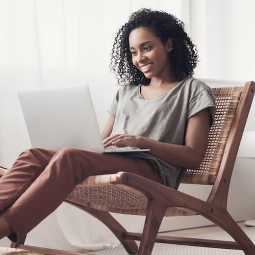 A woman using a laptop at home, likely managing finances or exploring real estate options online.