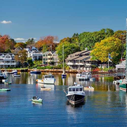 Coastline of Portland, Maine with houses along the shore and boats in the harbor.
