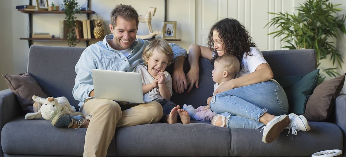 A family sitting comfortably on a couch, possibly in a home setting.