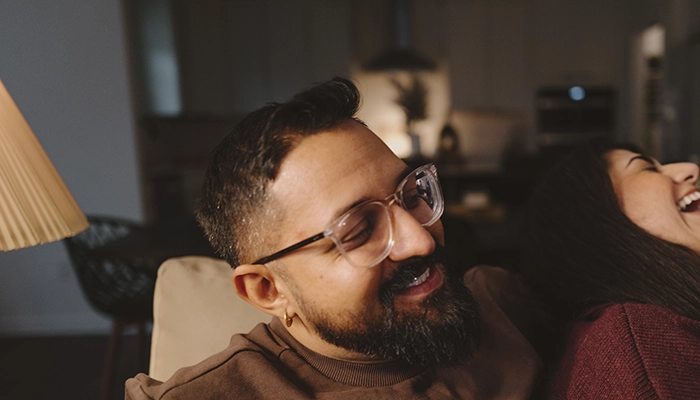 Man smiling holding woman who is laughing.