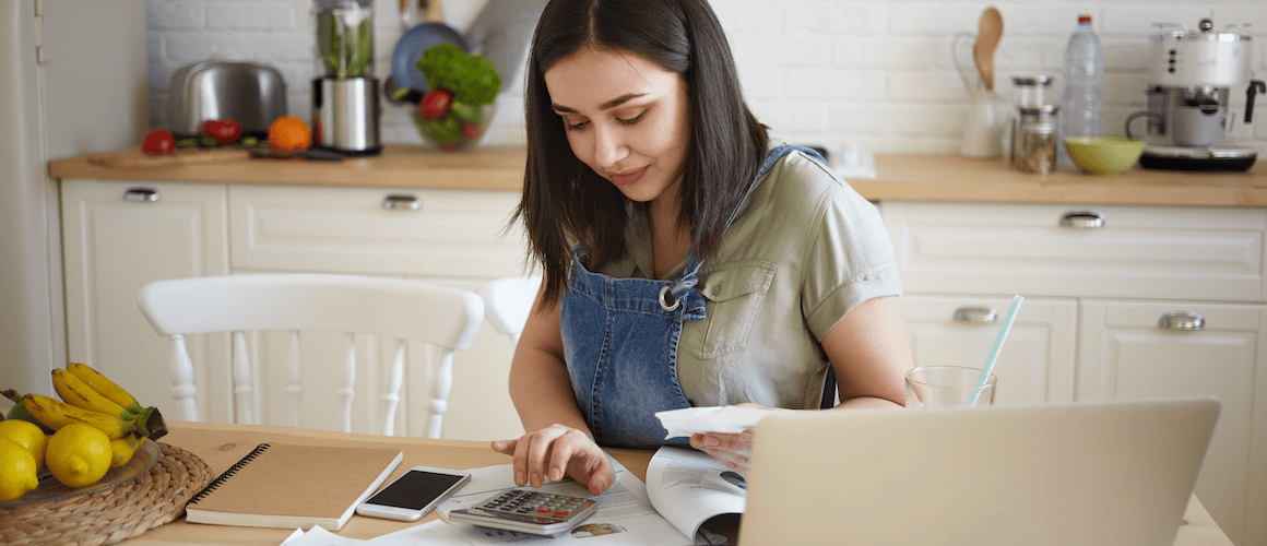 Young woman doing budget with calculator and laptop.