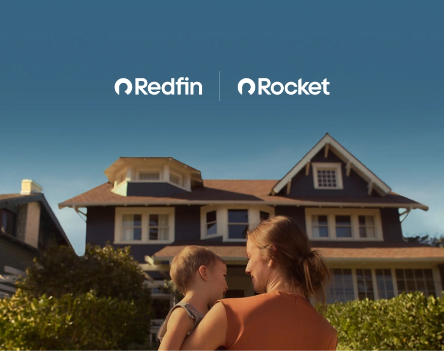 A mother holds a toddler on her hip while looking at the new house they bought with Redfin and Rocket Mortgage.