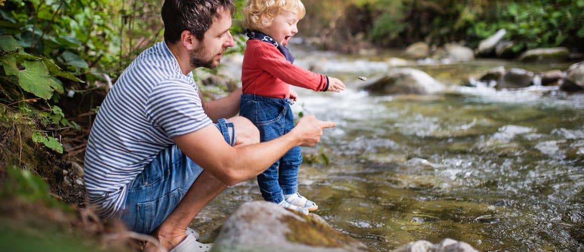 Image of man with his son hiking, stopped at river.