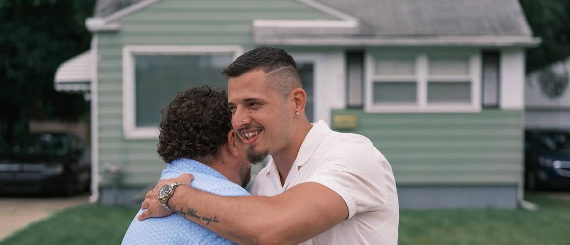 Realtor and client hugging in front of home.