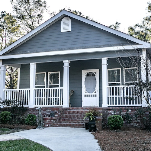 Small blue-gray mobile home with a front porch, potentially depicting a mobile or manufactured home design.
