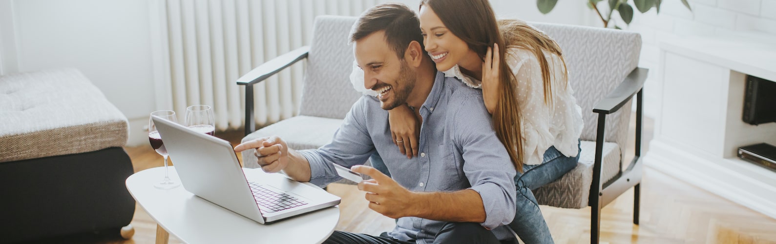 A young couple smiling and looking at the laptop screen.