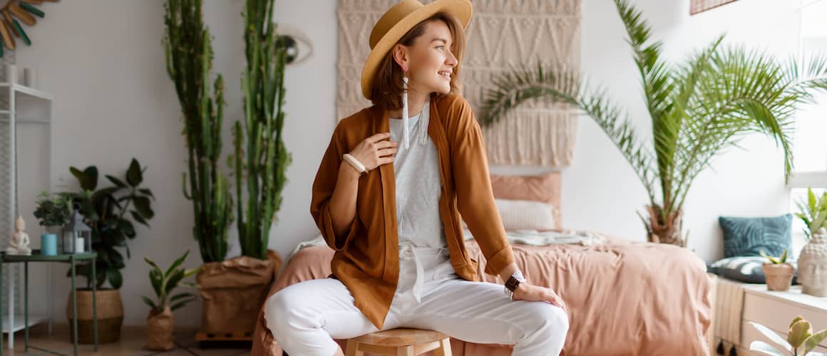 A fashionable women sitting on a stool looking outside, possible posing for a photo.