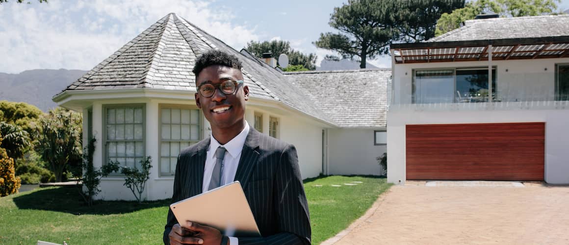 A real estate agent holding an iPad standing in front of a house possibly advertising it for sale.