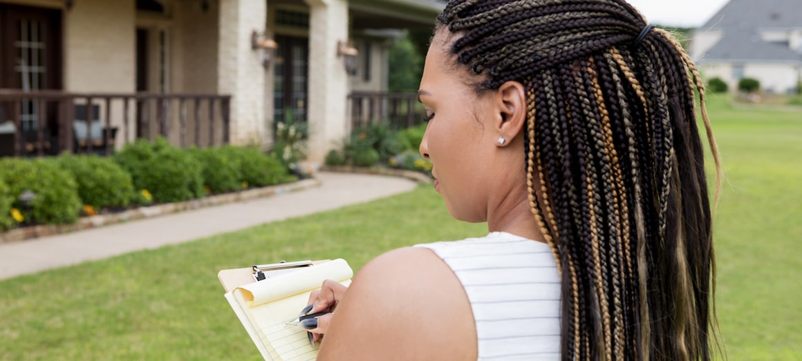 A woman appraising a home, indicating property assessment or valuation in real estate.