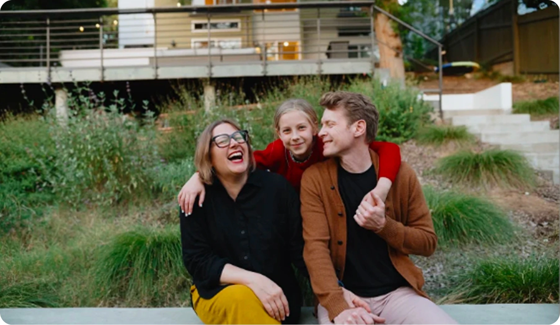 Family sitting outside a modern home, smiling together