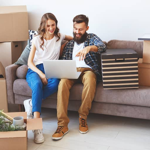 A happy couple moving into their new place surrounded by boxes.