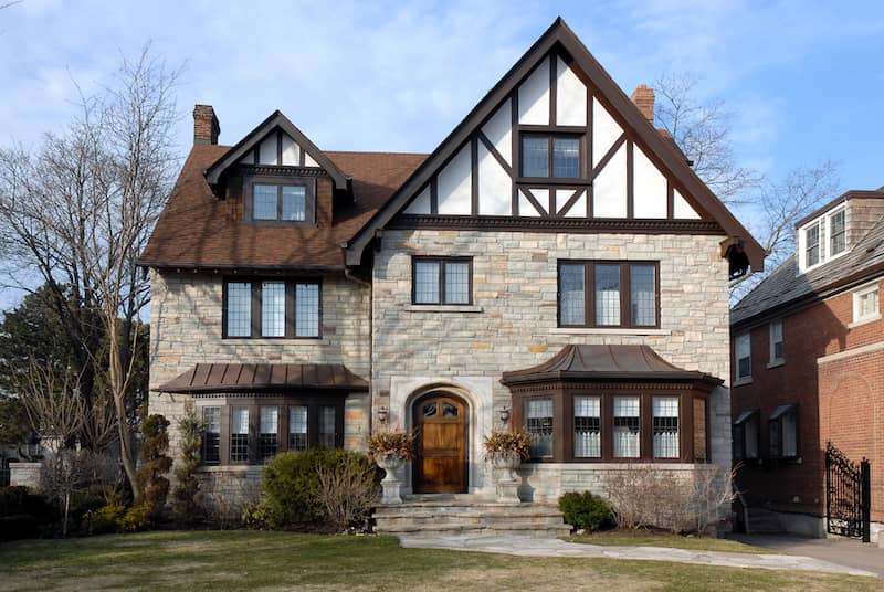 Brick tudor style house with ornate wooden door.