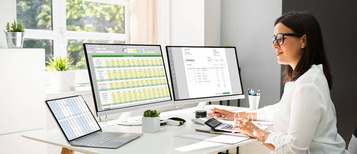 Woman filing freelance taxes on computer with second monitor.