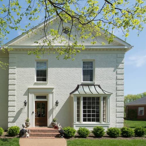 Two story white brick home in spring.