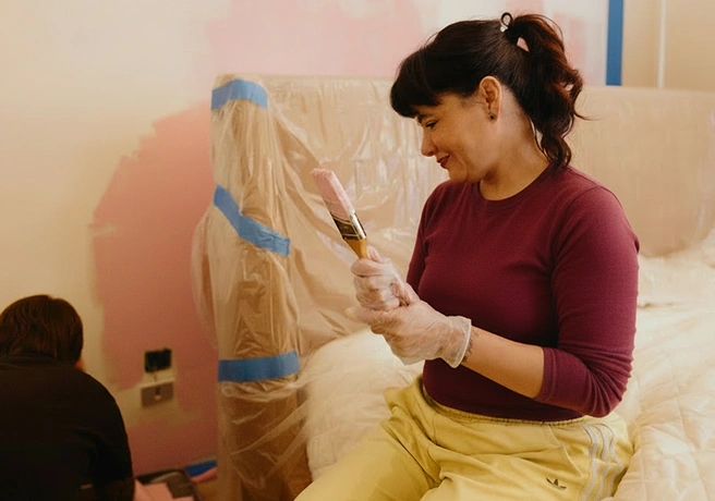 Woman holding a paintbrush while painting a room