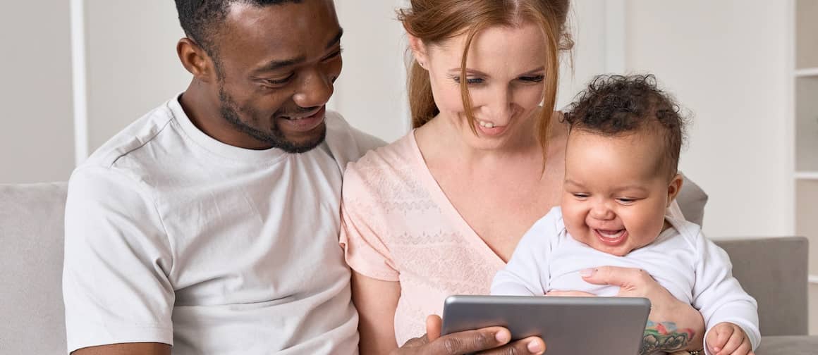 RHB Assets From IGX: Happy couple with a baby browsing for homes online using a laptop.