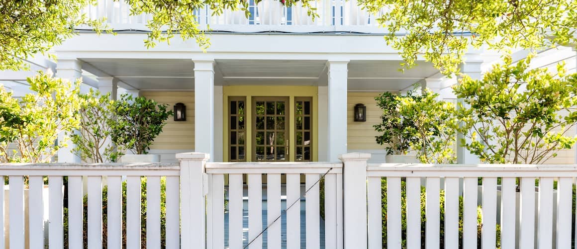 Wooden architecture of a house door leading to a front porch and yard with green landscaping, portraying a welcoming entrance.