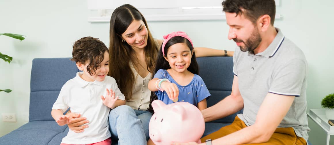 Family with two young children holding piggybank together.