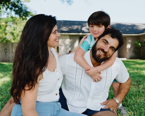 A young family of three spending time together in the front yard of their home.