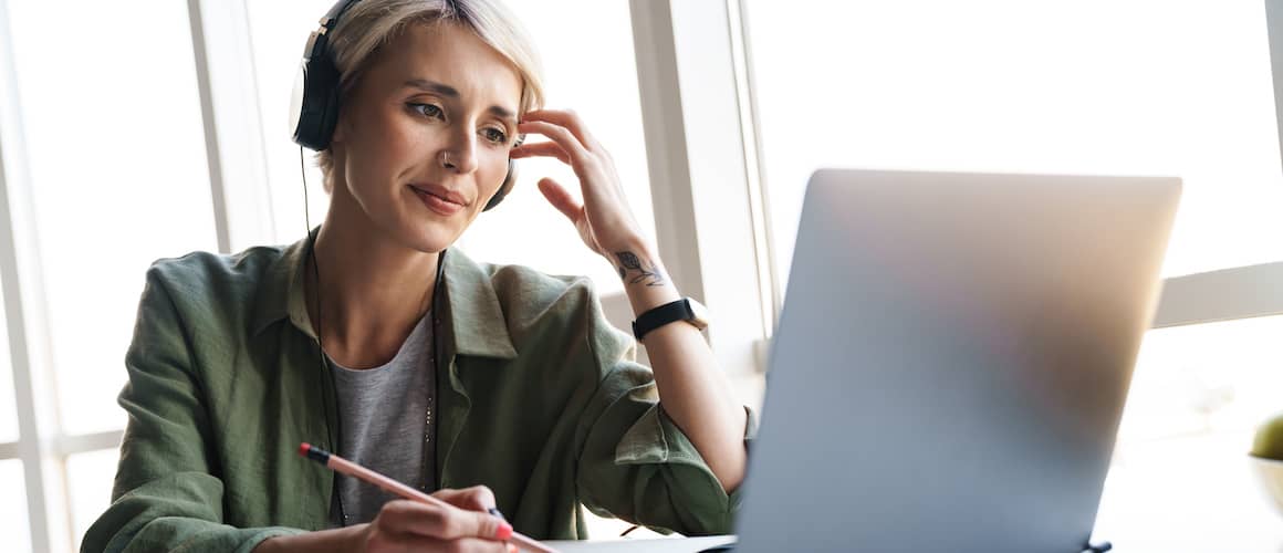 A woman with headphones on a computer, possibly working or relaxing at home.