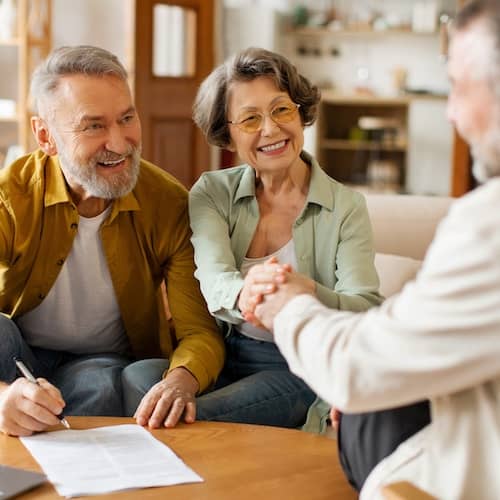 A couple engaging in a discussion with one other individual while signing paperwork.