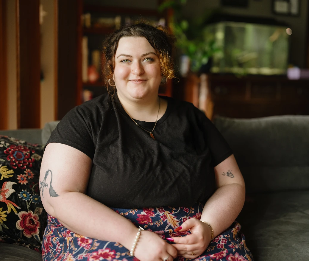 A woman smiles while sitting on her living room couch.