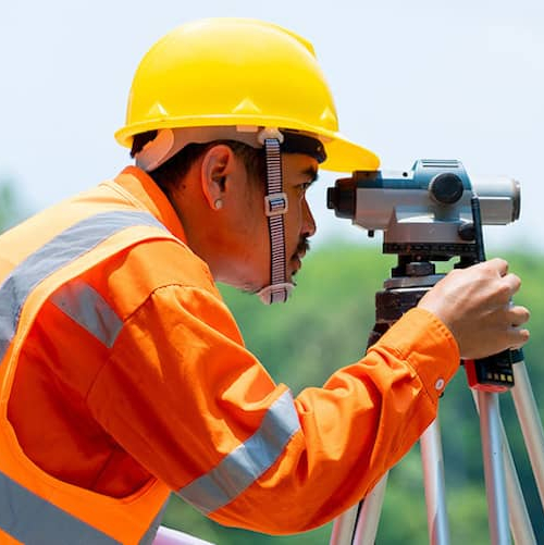 A land surveyor working in a field, illustrating a professional conducting a land survey.