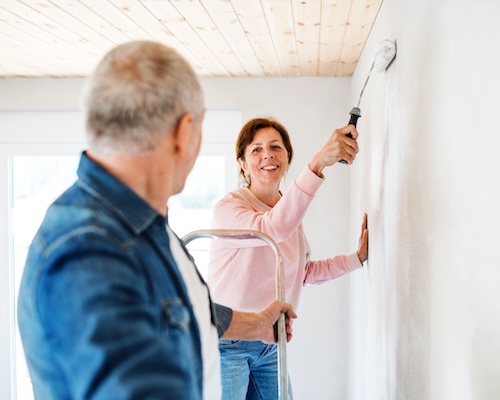 Couple painting a wall a fresh coat of paint.