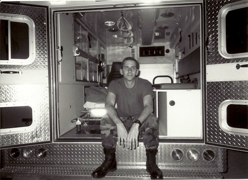 Man in uniform sitting on the back of a truck.