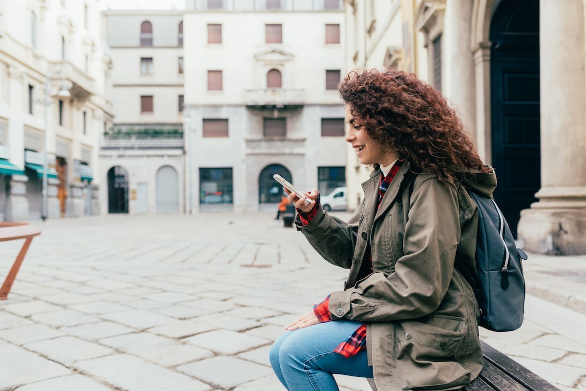 RHB Assets From IGX: Young woman talking on the phone while browsing her laptop.