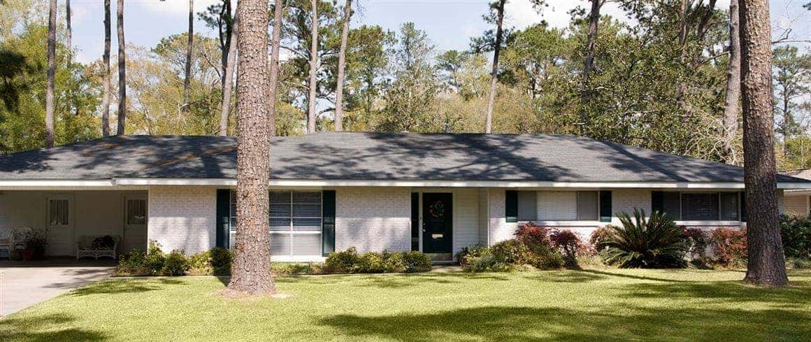 A rambler house with a white brick exterior, showcasing a single-story residence with a clean and classic design.