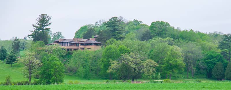 Frank Lloyd Wright's Taliesin home outside Madison Wisconsin, surrounded by lush green field and trees.