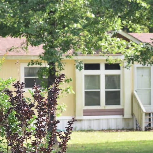 A manufactured home in springtime surroundings, possibly in a suburban area.