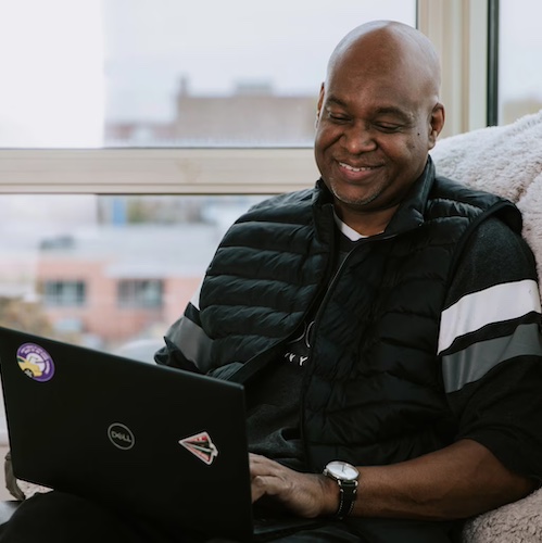 Man relaxing on couch while using laptop.