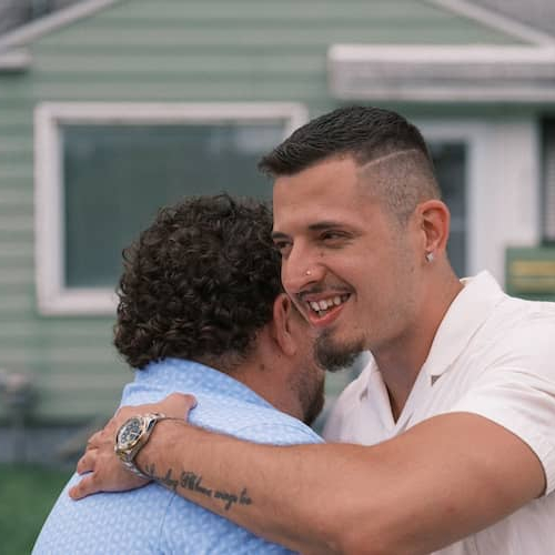 Realtor and client hugging in front of home.