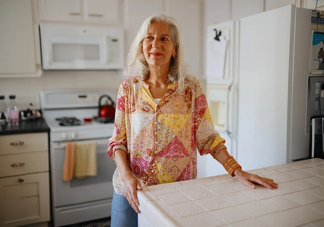 Older woman standing in a kitchen by a countertop