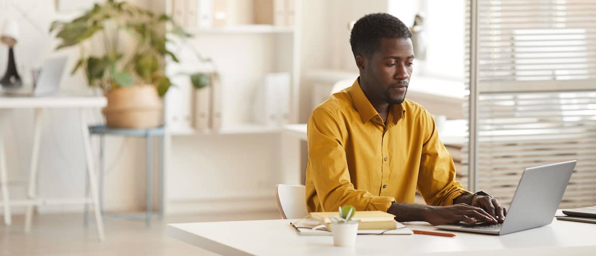 African American man working on a laptop at a desk.