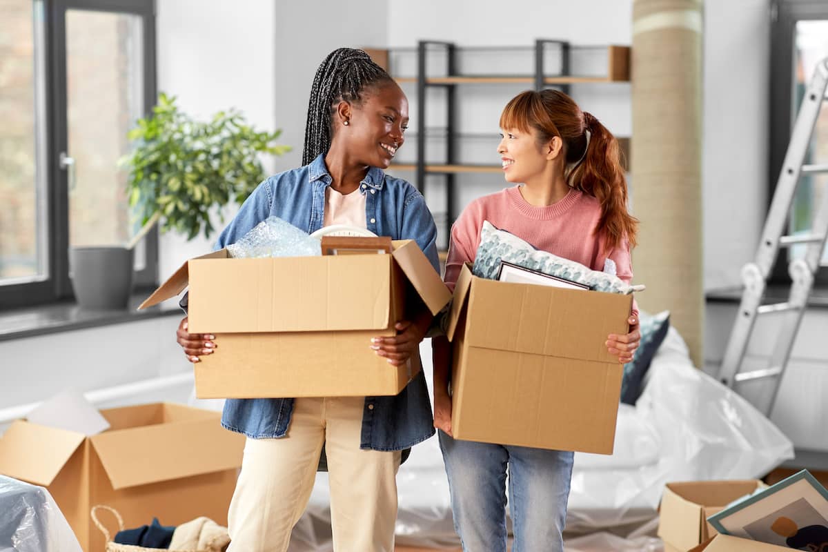 moving people in bright house - happy smiling women with boxes at new home