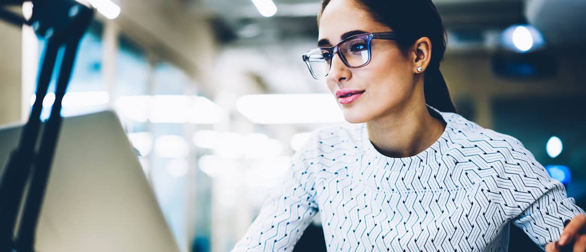 A women with glasses working on something on her laptop.